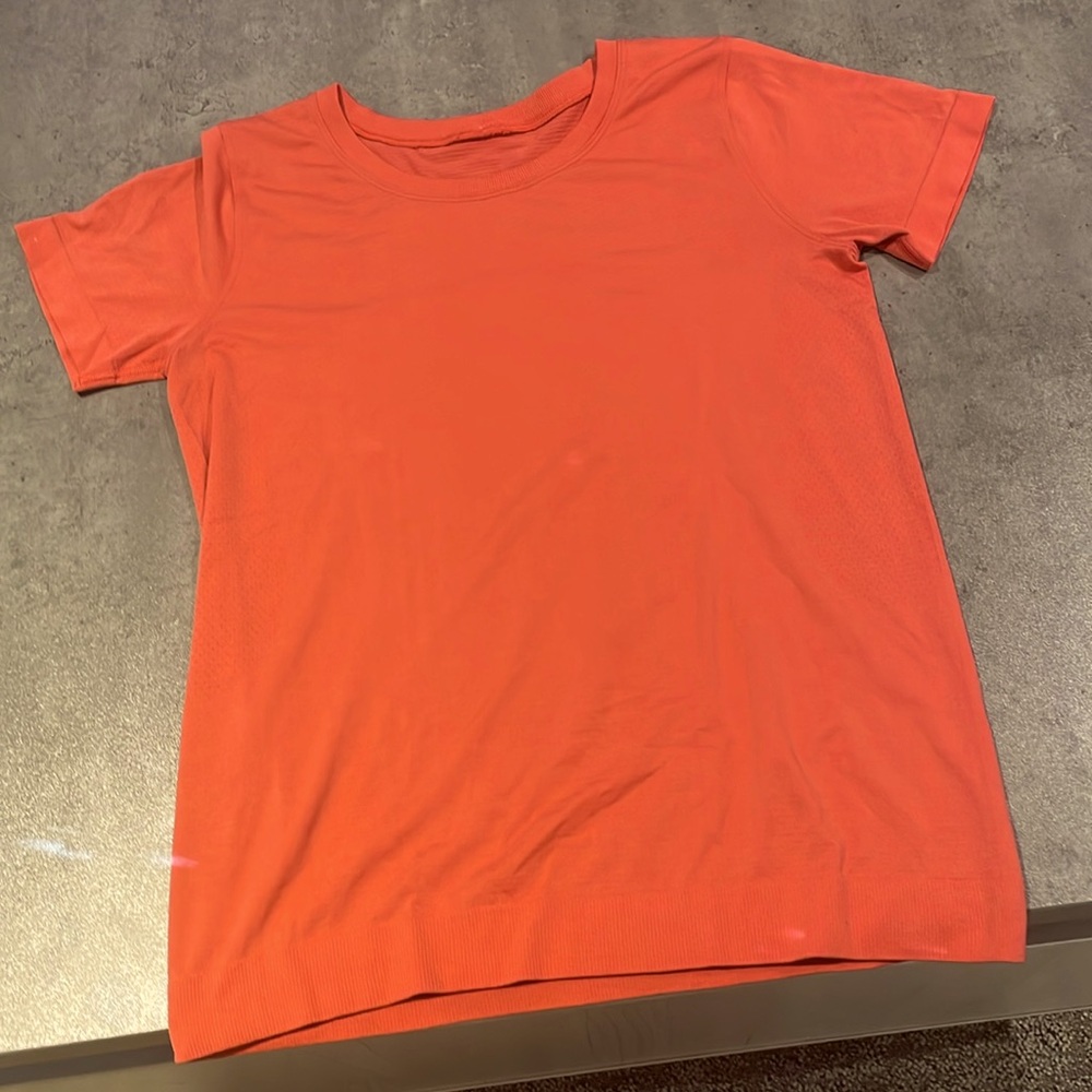 a reddish-orange lululemon swiftly tech in size 6.